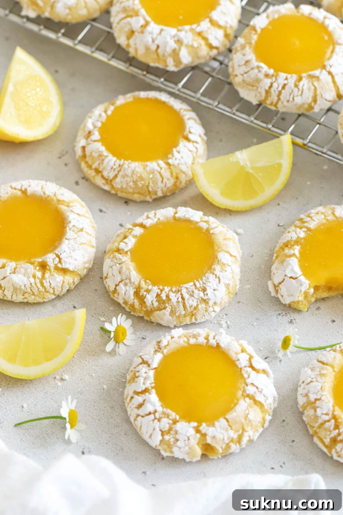 Zesty Gluten-Free Lemon Curd Gems 8 Gluten-free lemon curd thumbprint cookies cooling on a wire rack after being baked, showing their crinkled edges and glistening lemon curd centers.