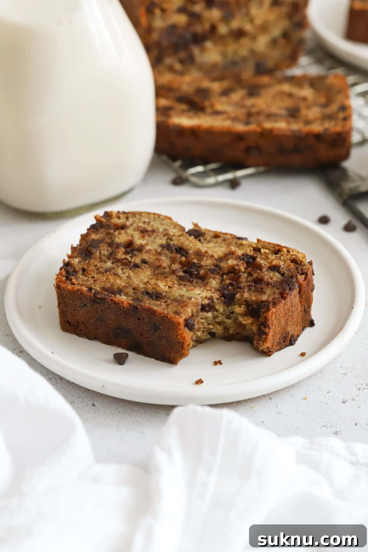 A delectable slice of gluten-free chocolate chip banana bread, with a bite taken out, showcasing its moist crumb and melty chocolate.